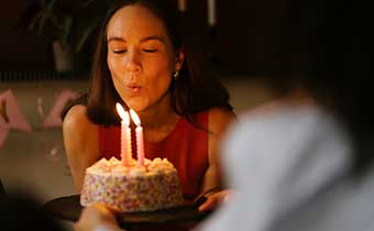 woman blowing out candles at a birthday cake